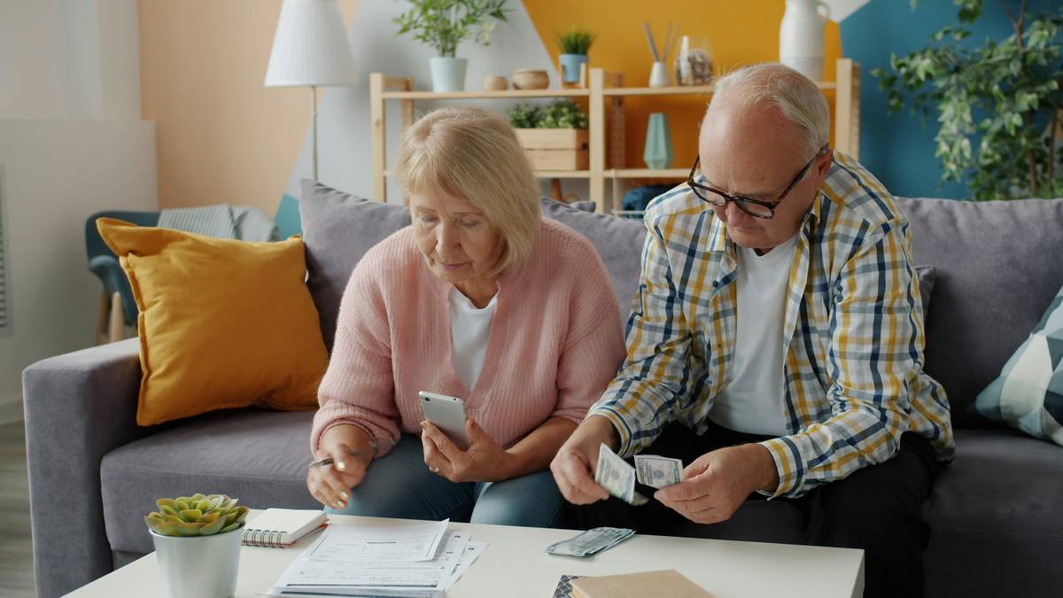 Senior couple reviewing long term care insurance benefits paperwork with financial advisor at kitchen table